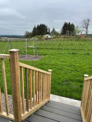 a wooden deck with a view of a soccer field at Drovers Lodge, farm retreat in rural Lanarkshire, family and pet friendly, onsite craft distillery, perfect location for exploring central Scotland in Forth