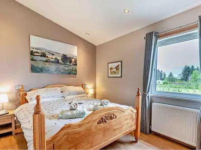 a bedroom with a wooden bed and a window at Drovers Lodge, farm retreat in rural Lanarkshire, family and pet friendly, onsite craft distillery, perfect location for exploring central Scotland in Forth