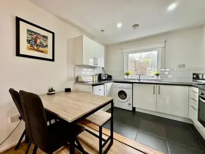 a kitchen with a wooden table and a dining room at Fifty Five on Gilmour Street in Eaglesham