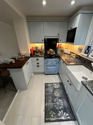 a kitchen with white cabinets and a kitchen rug on the floor at Angel Cottage, Strone in Dunoon