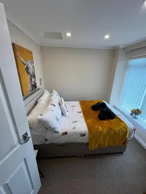 a bedroom with a bed with a yellow blanket on it at Angel Cottage, Strone in Dunoon