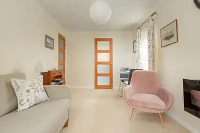 a living room with a couch and a pink chair at Lovely Edinburgh Home - Craighouse Gardens in Edinburgh