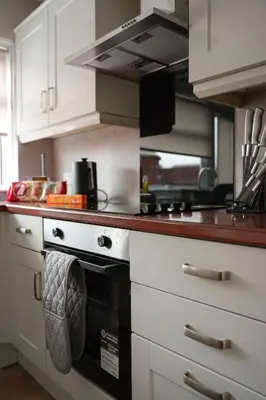 a kitchen with white cabinets and a stove top oven at 4 BDR House By Caledonia Luxe Stays Short Lets & Serviced Accommodation Livingston in Livingston