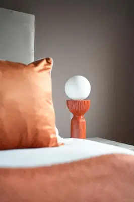 a bed with a orange pillow and a lamp at 4 BDR House By Caledonia Luxe Stays Short Lets & Serviced Accommodation Livingston in Livingston