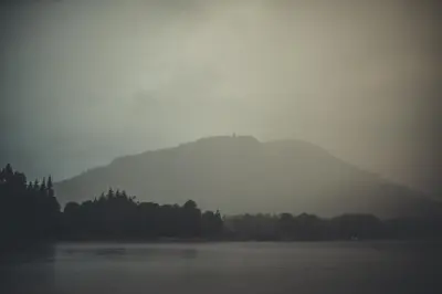 a misty view of a mountain and a lake at NICHT' Apartments Inveraray Town Centre in Inveraray
