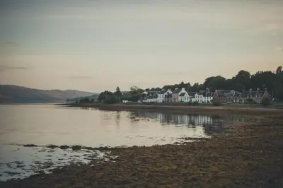 a group of houses on the shore of a body of water at NICHT' Apartments Inveraray Town Centre in Inveraray