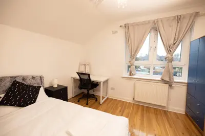 a bedroom with a bed and a desk and a window at Knightswood in Knightswood