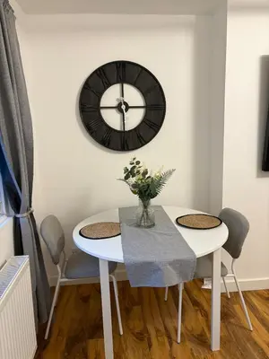 a dining room with a table and a clock on the wall at Premium Village Stay near Train & Loch in Lochwinnoch