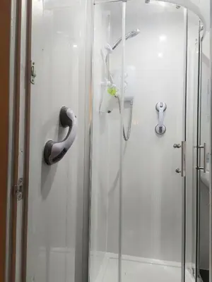 a shower with a glass door next to a shower at The Wee Nest in Largs - One-Bedroom Ground Flat in Largs