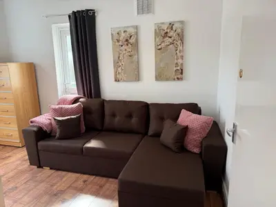 a living room with a brown couch and two paintings at Clapham Road Apartment in Moffat
