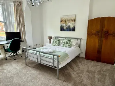 a bedroom with a bed and a desk and a computer at Clapham Road Apartment in Moffat