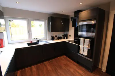a kitchen with black cabinets and a sink at Edinburgh West Luxury 5 Bedroom Home in Edinburgh