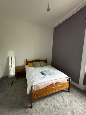 a bedroom with a large bed with a wooden frame at Victorian 5 Bedroom House Free Parking SSE Central in Glasgow