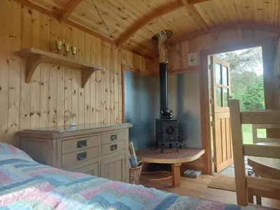 a bedroom with a stove in a wooden cabin at Shepherd's Hut Harmony at A Therapeutic Space in Moniaive