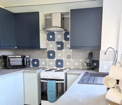 a kitchen with blue cabinets and a white stove top oven at Fairway house in Campbeltown