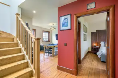 a hallway with stairs and a red wall at Blà Bheinn by Birch Stays in Dunollie