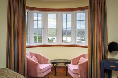 a room with two chairs and a table and windows at Blà Bheinn by Birch Stays in Dunollie