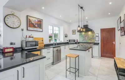 a kitchen with white cabinets and a clock on the wall at Blà Bheinn by Birch Stays in Dunollie