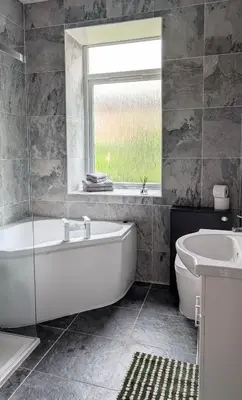 a bathroom with a tub and a sink and a window at Whisky Row in Campbeltown