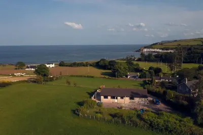 an aerial view of a house in a field with the ocean at Bridie's Cottage in Ballymena