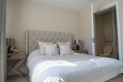 a white bedroom with a large white bed with pillows at Ardlui House Gardens in Hamilton
