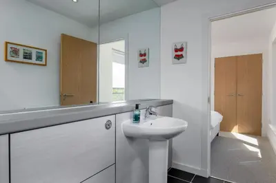 a white bathroom with a sink and a mirror at The Stirling Penthouse - Free Parking in Stirling
