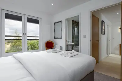 a white bedroom with a large white bed and windows at The Stirling Penthouse - Free Parking in Stirling