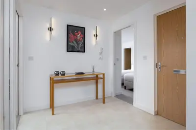 a hallway with a wooden table and a bedroom at The Stirling Penthouse - Free Parking in Stirling