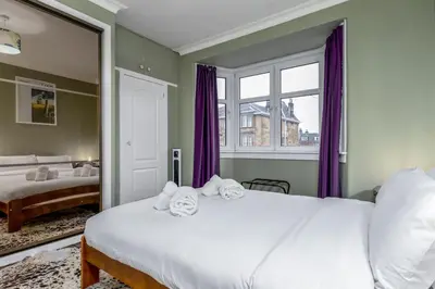 a bedroom with a large bed with purple curtains at Tranquil Glasgow Retreat in Glasgow