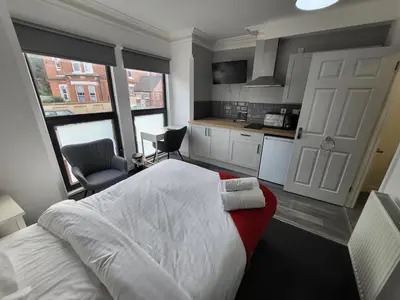 a bedroom with a large bed and a kitchen at Fishpond Family Suite in Moffat