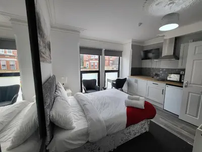 a bedroom with a large bed and a kitchen at Fishpond Family Suite in Moffat