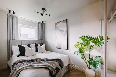 a bedroom with a bed with black and white pillows at JW Executive ApartHouse in Glasgow
