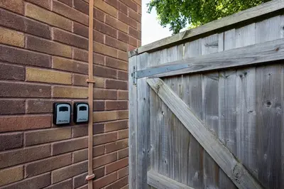a brick wall with a wooden gate and a door at Luxury Flat Near Hove Station parking sleeps 4 in Moffat