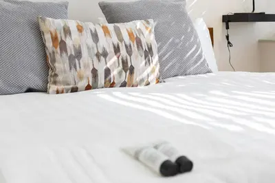 a remote control on a white bed with a pillow at Luxury Flat Near Hove Station parking sleeps 4 in Moffat