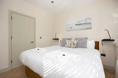 a bedroom with a large bed with white sheets at Luxury Flat Near Hove Station parking sleeps 4 in Moffat