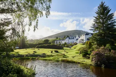 a view of a river with houses in the background at Macdonald Forest Hills Resort in Aberfoyle