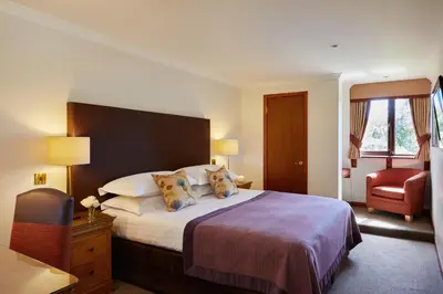 a hotel room with a bed and a chair at Macdonald Forest Hills Resort in Aberfoyle
