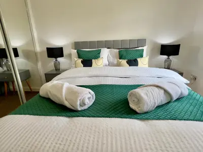two beds with towels on them in a bedroom at Stylish City Apartment with Free Parking near Town in Glasgow