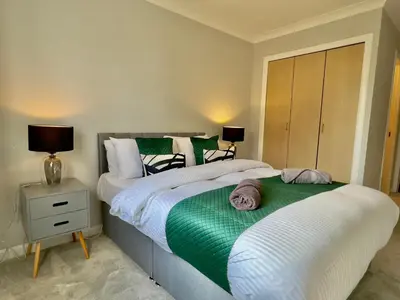 two beds in a bedroom with a green blanket at Stylish City Apartment with Free Parking near Town in Glasgow