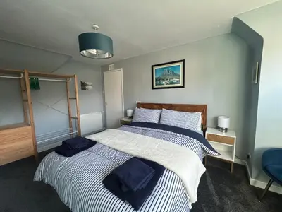 a bedroom with two beds and a blue chair at 29 Carnoch, Glencoe Village in Glencoe