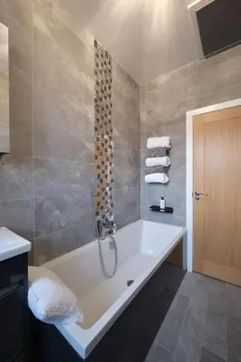 a bathroom with a bath tub with a shower at Stay Torrance-Village Home Near Glasgow in Glasgow