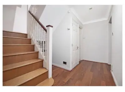 a hallway with stairs and a white door in a house at 14 Maple Mews in Moffat