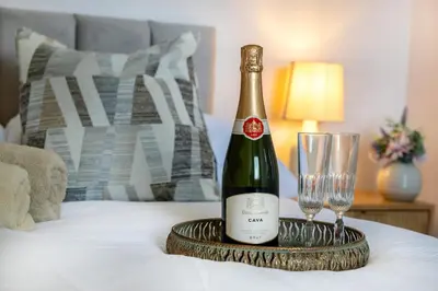 a bottle of champagne and a glass on a bed at Modern 3 Bedroom home in Kings Park in Polmadie