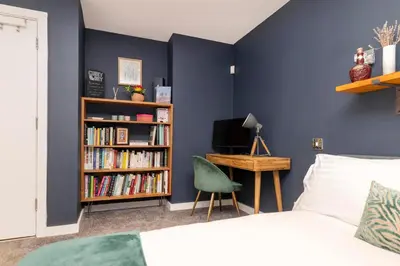 a bedroom with a blue wall with a bed and a desk at Chic Edinburgh 3-Bedroom 2-Storey House near City Centre with Free Parking in Edinburgh