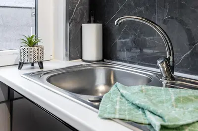a kitchen sink with a green towel in it at Cosy 3 bed flat in Kings Park in Glasgow