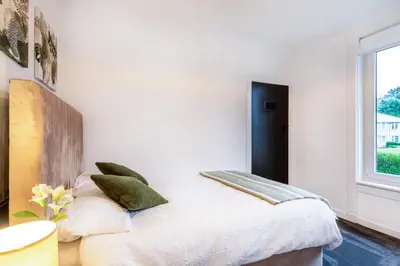 a white bedroom with a bed with green pillows at Cosy 3 bed flat in Kings Park in Glasgow