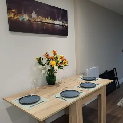 a wooden table with blue plates and a vase of flowers at Riverside Apartment in Moffat