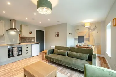 a living room with a green couch and a kitchen at Stunning upper villa stay in the City! in Edinburgh