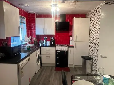 a kitchen with red brick walls and white cabinets at Stylish 3 bedroom house in Glasgow