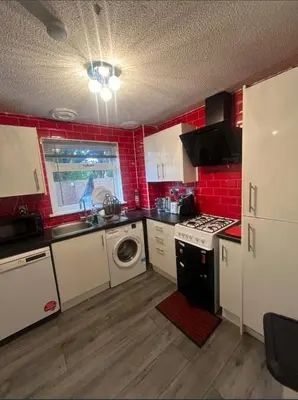 a kitchen with red brick walls and a sink and a stove at Stylish 3 bedroom house in Glasgow